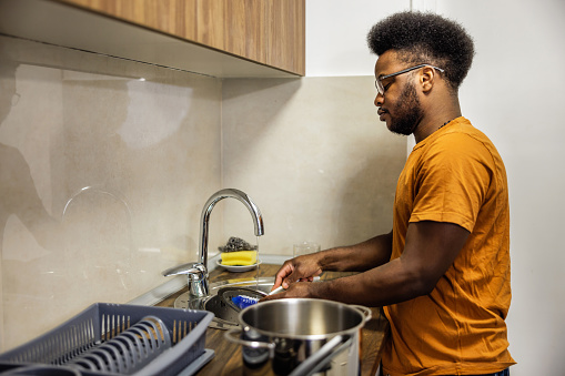 Young man washing dishes at home