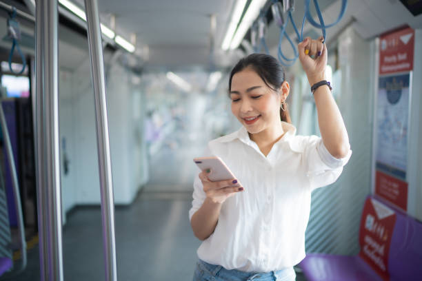 istock Young Asian woman using application in smartphone and smile while standing in metropolitan sky train , woman connecting with technology concept. 1720662033