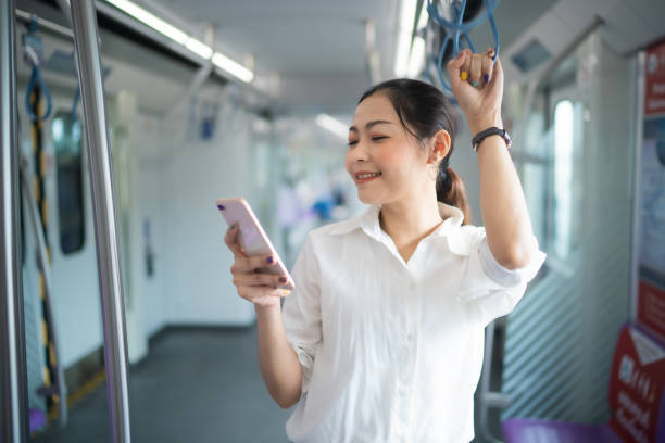 istock Young Asian woman using application in smartphone with positive emotion while standing in metropolitan sky train , woman connecting with technology concept. 1720662042