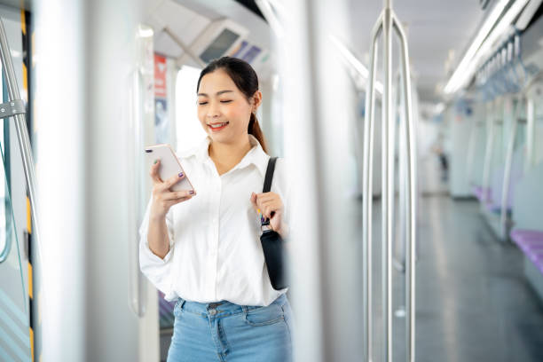 istock Young Asian woman looking application in smartphone with positive emotion while standing in metropolitan sky train ,woman connecting and using technology in smart city concept. 1720663138