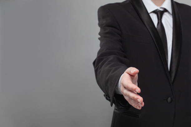 Handshake, business and agreement concept.  Human hand against grey studio wall background