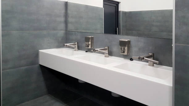 istock Bathroom interior in black and white. Round ceramic washbasins. Mirrors, plastic soap dish and chrome faucets for washing hands after a toilet. Design with dark facing tiles. 1720667830