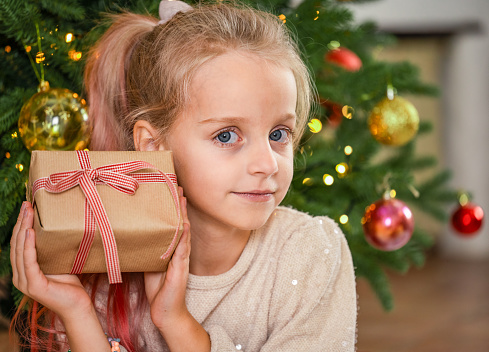 Young Girl Holding a Christmas Present and Smiles