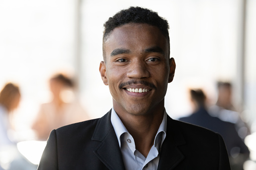 Head shot portrait smiling confident African American businessman in suit looking at camera, successful entrepreneur employee startup owner executive posing for corporate photo, standing in office