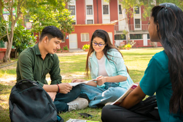 istock Students discussing together on a book in university campus ground. 1720690123