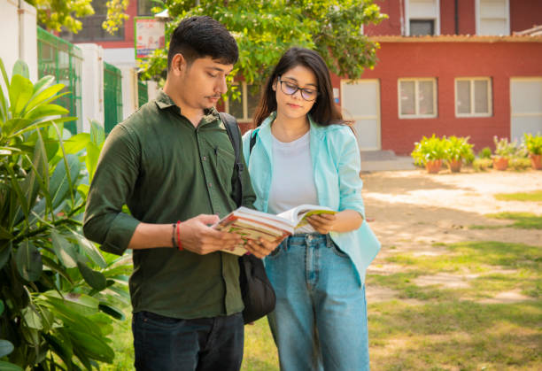 istock University students reading a book together in a campus. 1720690178