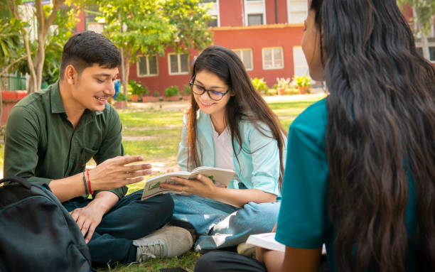 istock Students discussing together on a book in university campus ground. 1720690647