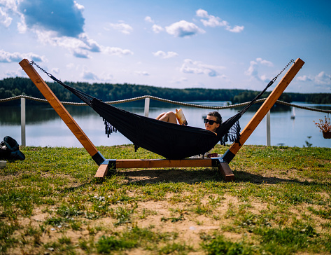 Summer vacation. Tourist on the holidays by the lake relaxing on a hammock