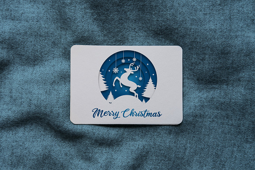 Christmas card with blue coloured paper cut style reindeer and Merry Christmas text.