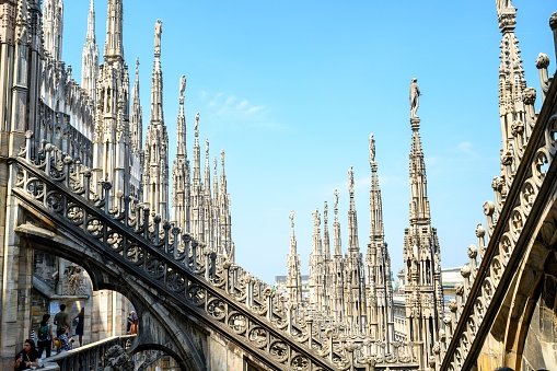 MIlan, Italy – June 18, 2023: Multiple columns view on the rooftop of the Milan Cathedral on a summer day, with blue sky background.