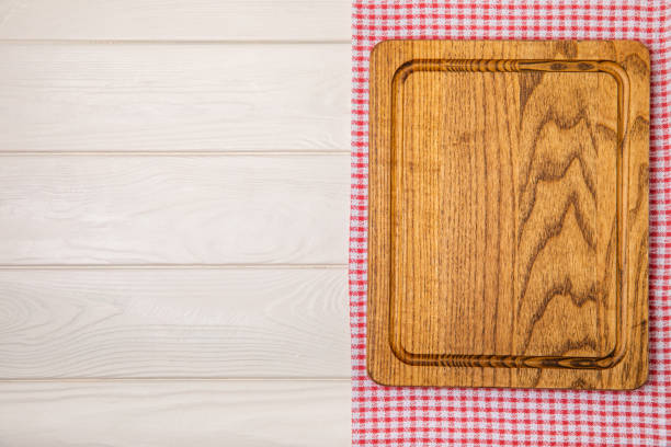 istock Wooden cutting board on a textured kitchen table. Wooden kitchen board and kitchen towel. Design.MOCKUP. Kitchenware. Place for text. Copy space. Recipe. Cooking concept. 1720763307