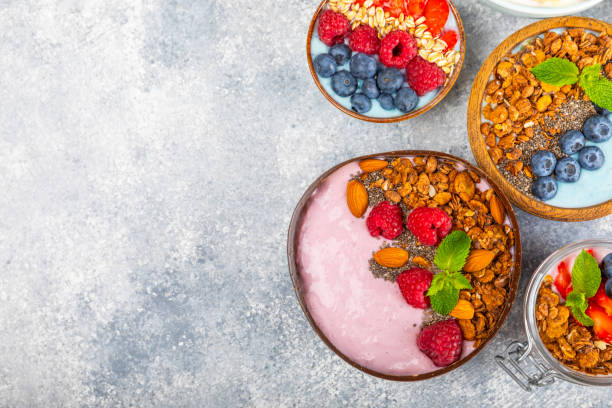 istock Useful breakfast. Granola bowl with yogurt and fresh berries on a textured kitchen table.Acai and spirulina bowl.Bowl of Greek yogurt with granola, almonds, blueberries, raspberries and strawberries. 1720763826