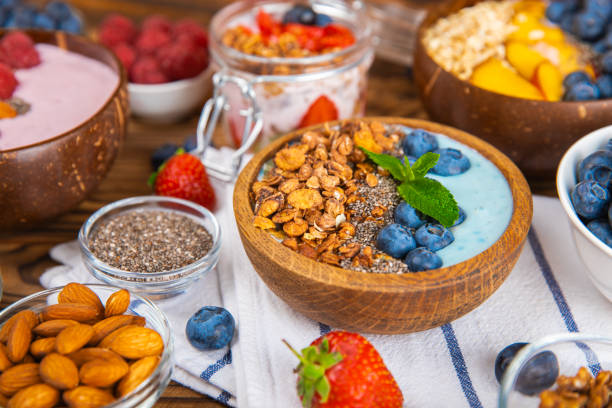 istock Useful breakfast. Granola bowl with yogurt and fresh berries on a textured kitchen table.Acai and spirulina bowl.Bowl of Greek yogurt with granola, almonds, blueberries, raspberries and strawberries. 1720763839