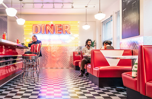 Customers sitting at the booths and bar counter of a retro style diner in Los Angeles, California.