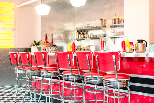 A row of red vinyl covered stools at the counter of a cafe in LA, California.