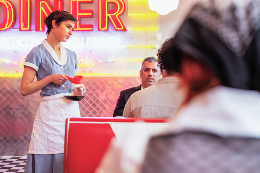 A woman listening to a customer as she works at a retro style diner in Los Angeles, California.