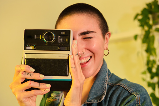 front view shot of a generation z female with big smile and shaved hair having fun taking some pictures with cool attitude and vintage clothes