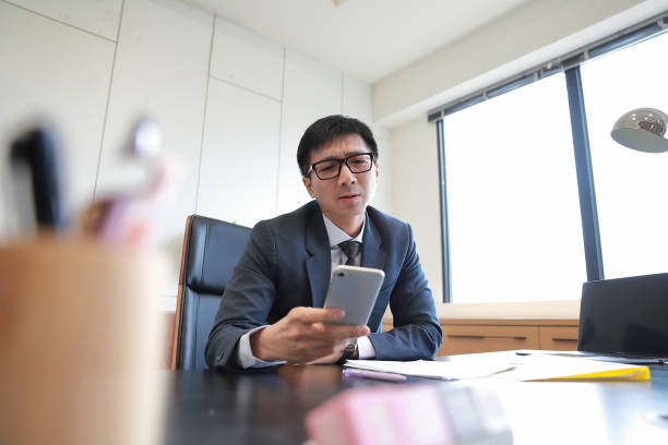 A supervisor is sitting at his desk working on documents A supervisor is sitting at his desk working on documents. His job is very stressful. 企業家 stock pictures, royalty-free photos & images