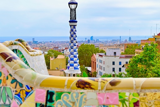 Barcelona, Spain: 10/05/2023- Parc Guell was commissioned by Eusebio Guell who wanted to creat a park for Barcelona aristocracy. The park contains organic looking columns made from stone, tile benches, buildings, and Gaudi dragons fountain.There is multi-corlored mosaic seats.