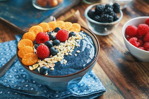 Blueberry Spirulina Smoothie in Bowl with Physalis, Berries and Superfoods on Top