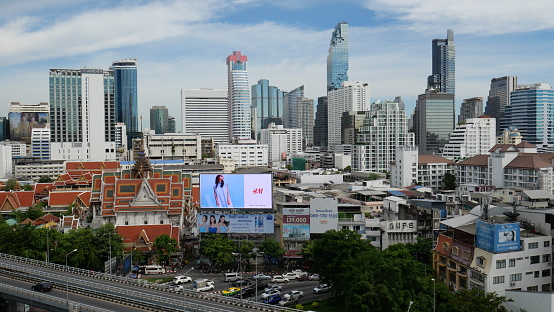 Bangkok, Thailand-June 3, 2021: City landscape, temple and ads in Bangkok. Cars are on the road.