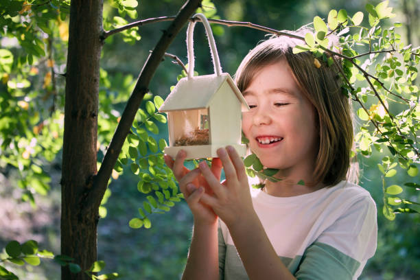 istock Smiling child hanging bird feeder on tree branch 1720945900