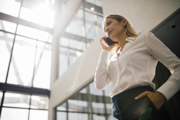 istock Business woman standing in office building and using mobile phone 1720980499