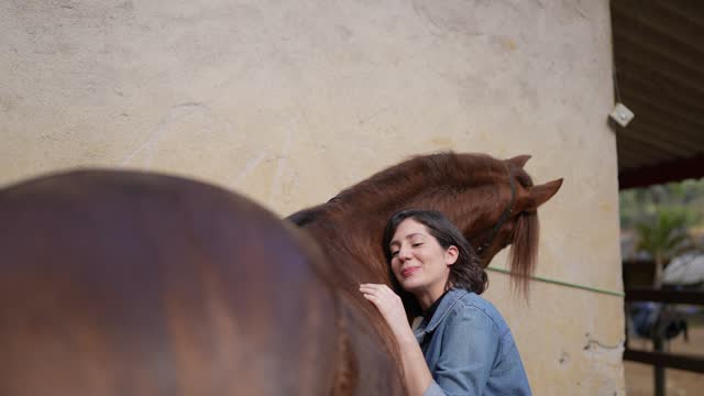 Young woman embracing her horse on a stable