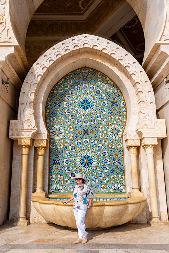 Mature woman in front of one of the water fountains of the Hassan II Mosque in Casablanca, Morocco. The mosque is one of the largest in the world.