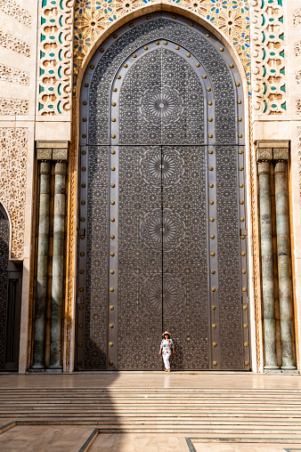 Mature woman in front of one of the doors of the Hassan II Mosque in Casablanca, Morocco. The mosque is one of the largest in the world.