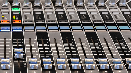 Control panel of a professional audio mixer for controlling live sound, indoor side view close-up