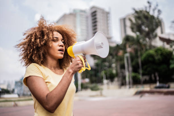 Young woman talking in a megaphone at city street