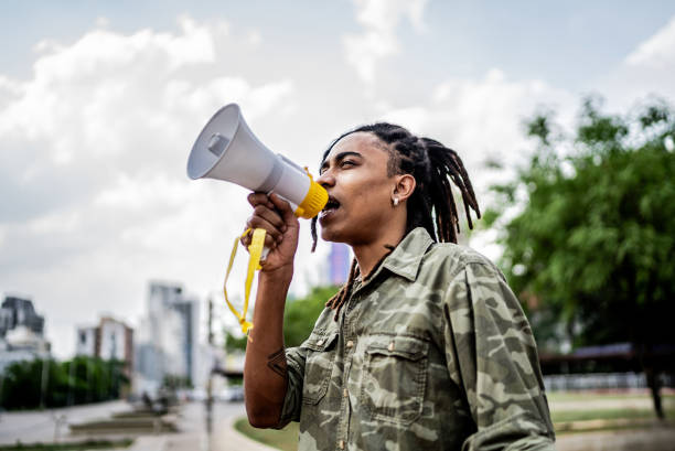Young man talking in a megaphone at city street