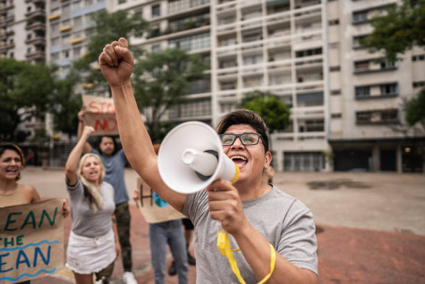 istock Mature man talking in a megaphone during a environmentalists protesting at city street 1721095473