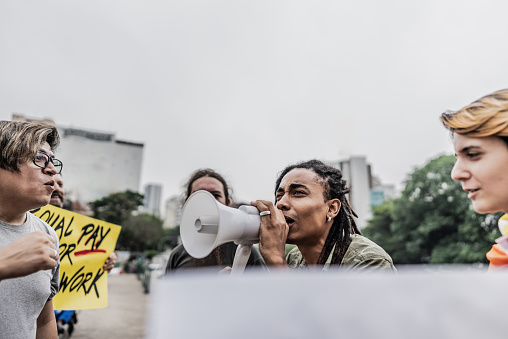 Young man talking in a megaphone during a protest in the street