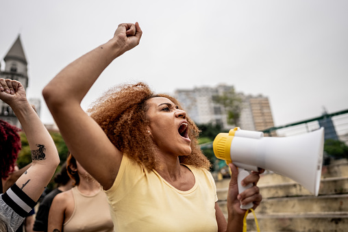Young woman talking in a megaphone during a protest in the street