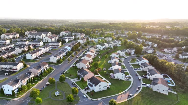 Aerial shot of American neighborhood during golden sunset. Drone orbit high above houses, homes, apartments, and duplexes.