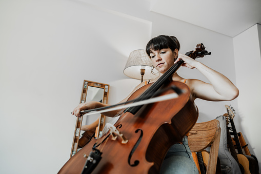 Young woman playing the cello in the apartment