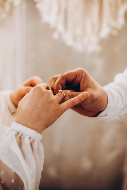 istock Groom putting the wedding ring on his bride's finger. Warm color 1721116614