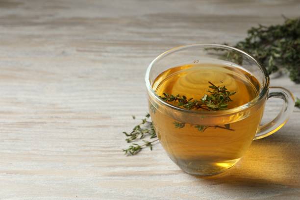 istock Cup of fresh thyme tea on wooden table, space for text 1721116620