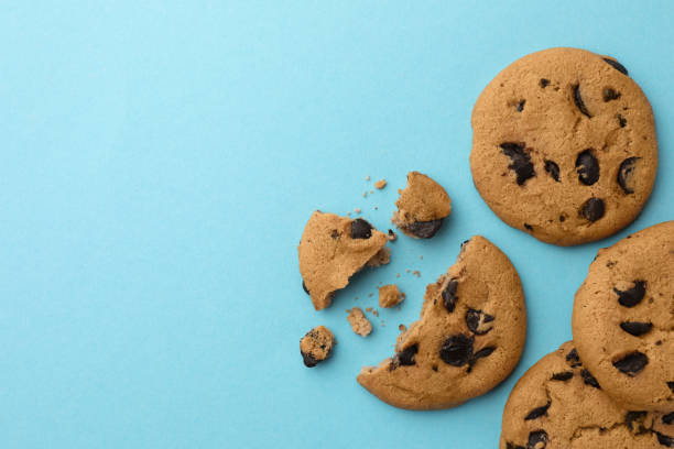 istock Many delicious chocolate chip cookies on light blue background, flat lay. Space for text 1721118243