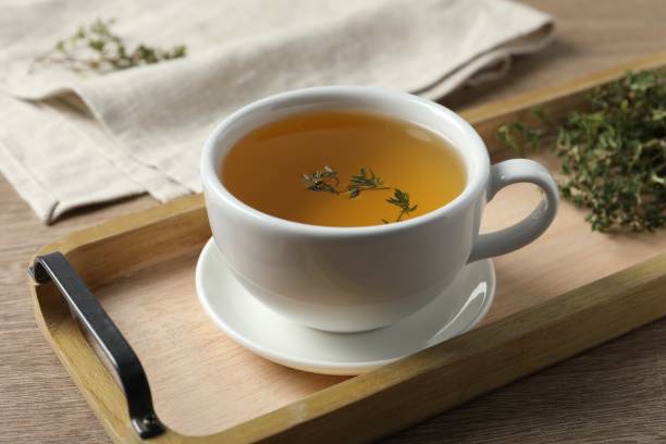 istock Cup of fresh thyme tea on wooden table, closeup 1721118249