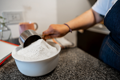 Close-up of a woman adding flour into a bowl