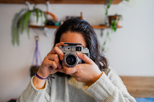 Young woman using photo camera at home