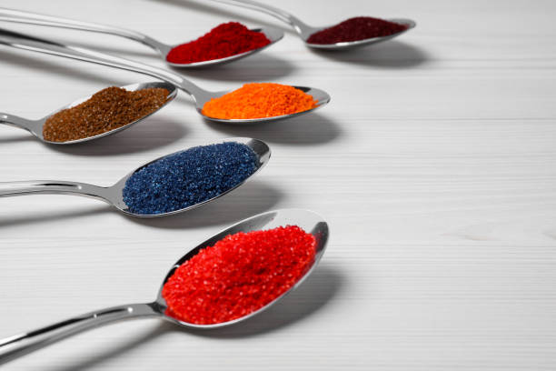 istock Spoons with different food coloring on white wooden table, closeup. Space for text 1721127598