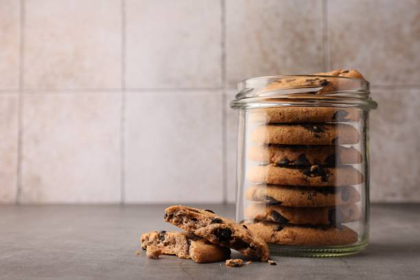 istock Glass jar with delicious chocolate chip cookies on grey table. Space for text 1721127732