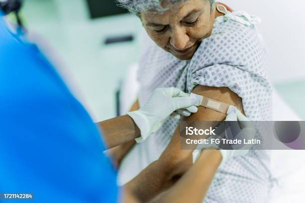Female Nurse Putting Adhesive Bandage On Senior Woman Pacients Arm After Vaccination At The Hospital Stock Photo - Download Image Now