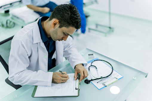 Doctor writing in a medical record in the hospital
