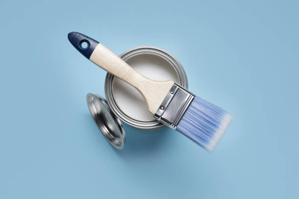 istock Can with white paint and brush on light blue background, top view 1721174142