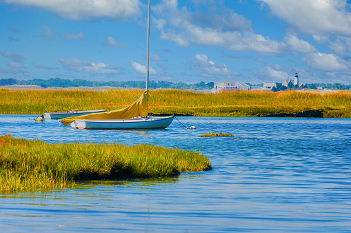 Two boats are moored in amid the golden salt marsh hues off Barnstable Harbor on Cape Cod